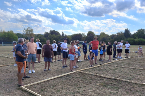 Boccia-Spieler versammeln sich auf einem trockenen Feld unter bewölktem Himmel.